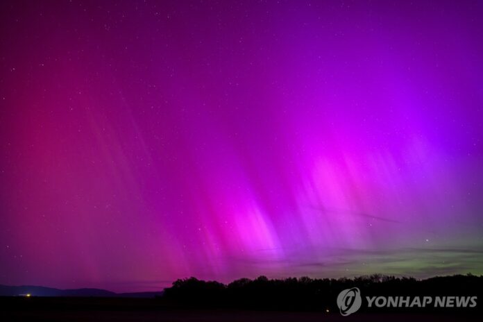 11일(현지시간) 스위스의 한 마을 하늘 위로 오로라가 나타나고 있다. [EPA 연합뉴스] 11일(현지시간) 스위스의 한 마을 하늘 위로 오로라가 나타나고 있다.